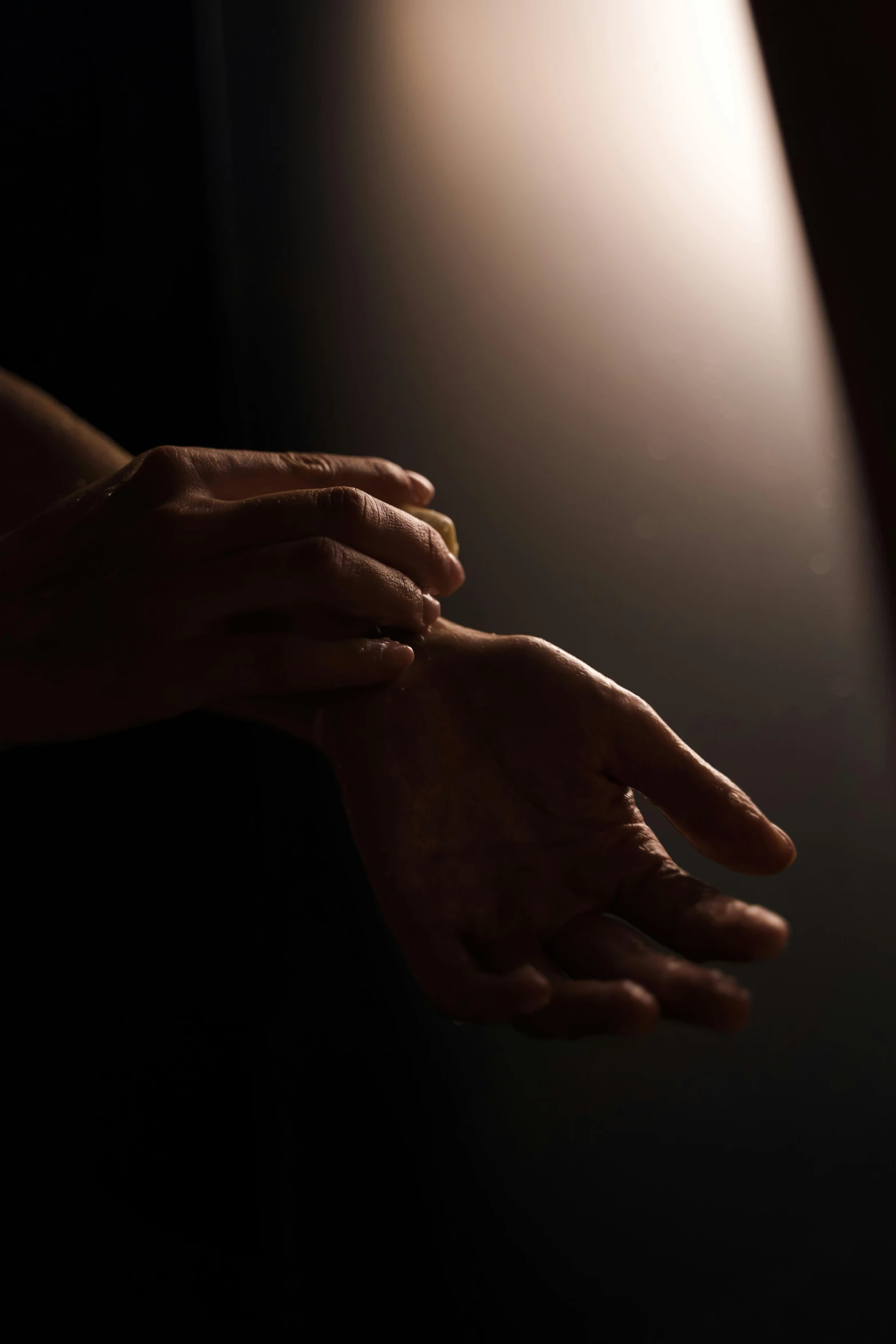 a person holding their hands in front of a light, inspired by Nan Goldin, unsplash, light and space, dramatic lowkey studio lighting, ignant, sunlit, praying