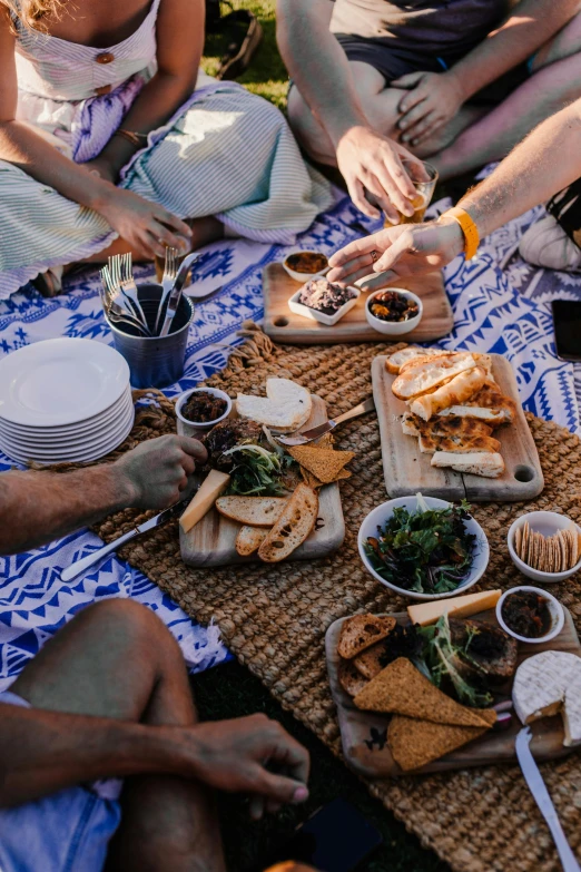 a group of people sitting around a picnic table, by Jessie Algie, pexels contest winner, eating a cheese platter, te pae, coastal, patterned