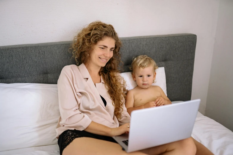 a woman and child sitting on a bed with a laptop, pexels, bralette, people at work, 1 5 0 4, upper body image