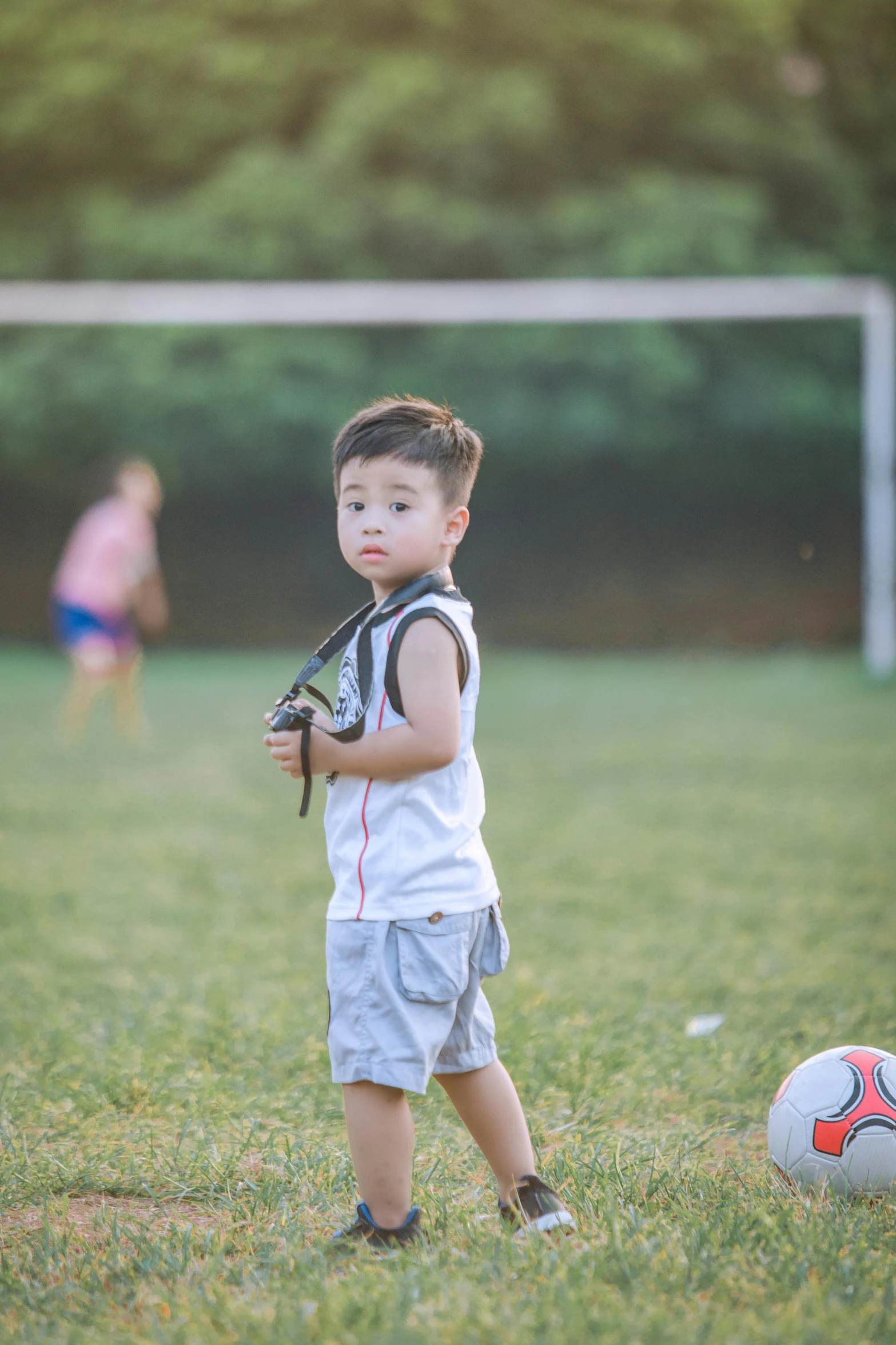 a young boy standing next to a soccer ball, a picture, by Reuben Tam, pexels contest winner, in a grass field, 15081959 21121991 01012000 4k, asian male, 256435456k film