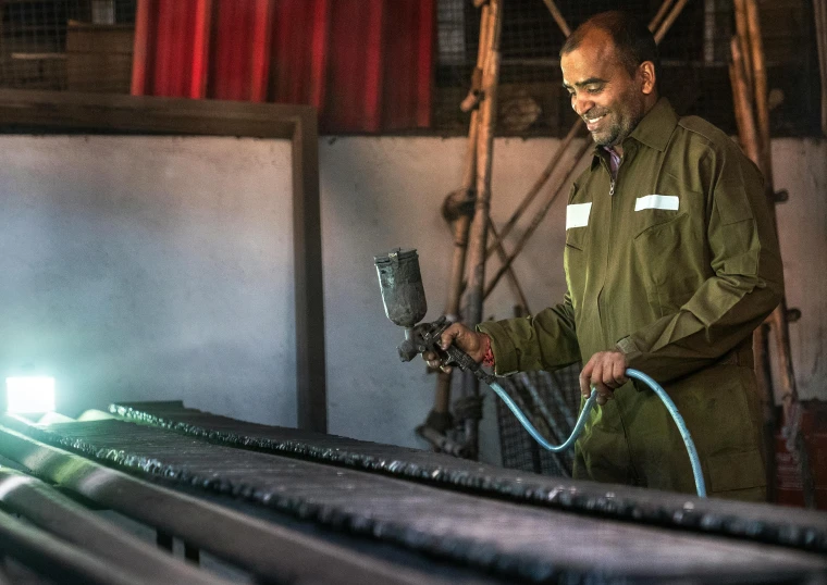 a man is working on a piece of metal, inspired by Afewerk Tekle, pexels contest winner, a still of a happy, steel mill, very high resolution, high quality upload