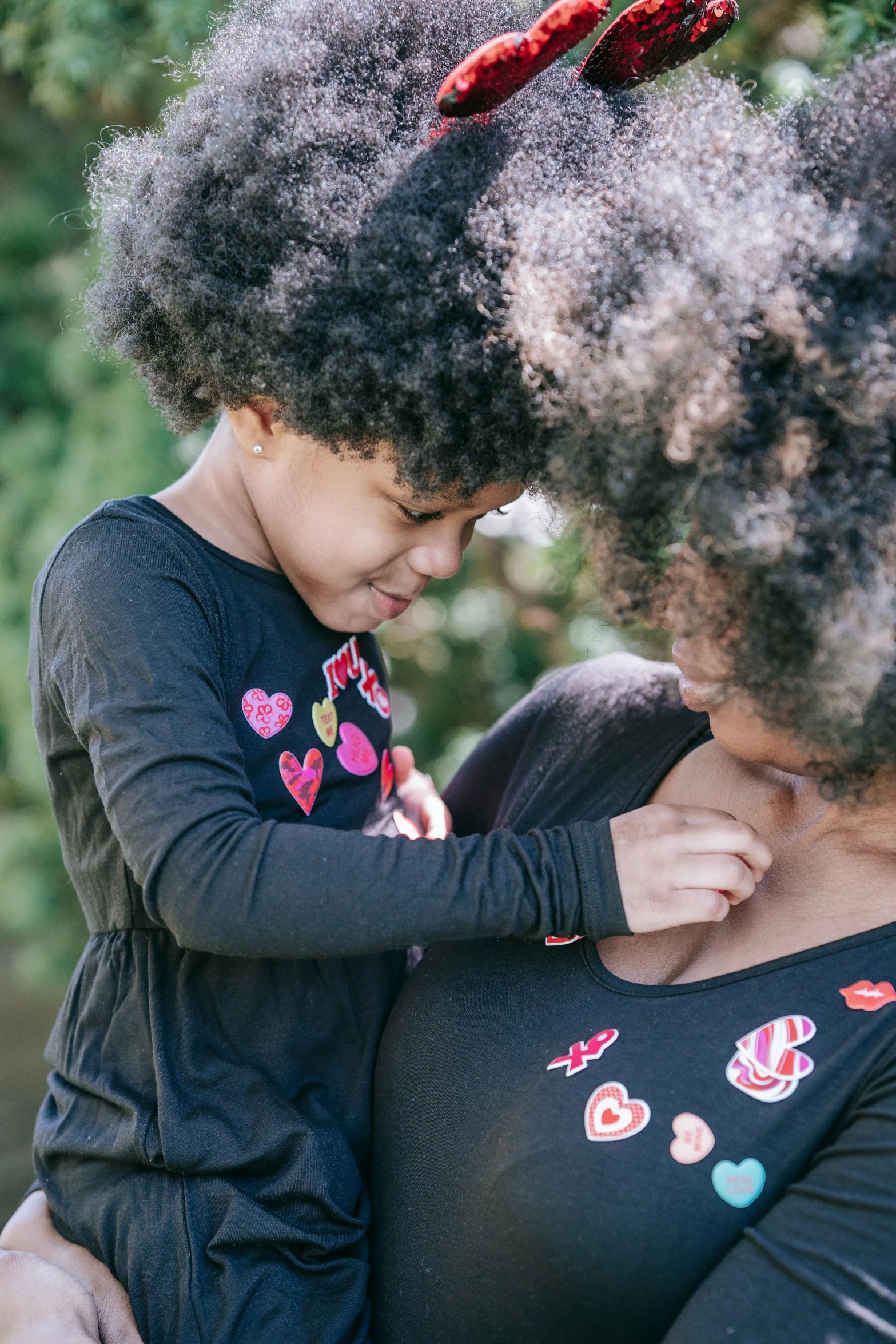 a woman holding a child in her arms, pexels contest winner, natural hair, touching her clothes, hearts, panel of black