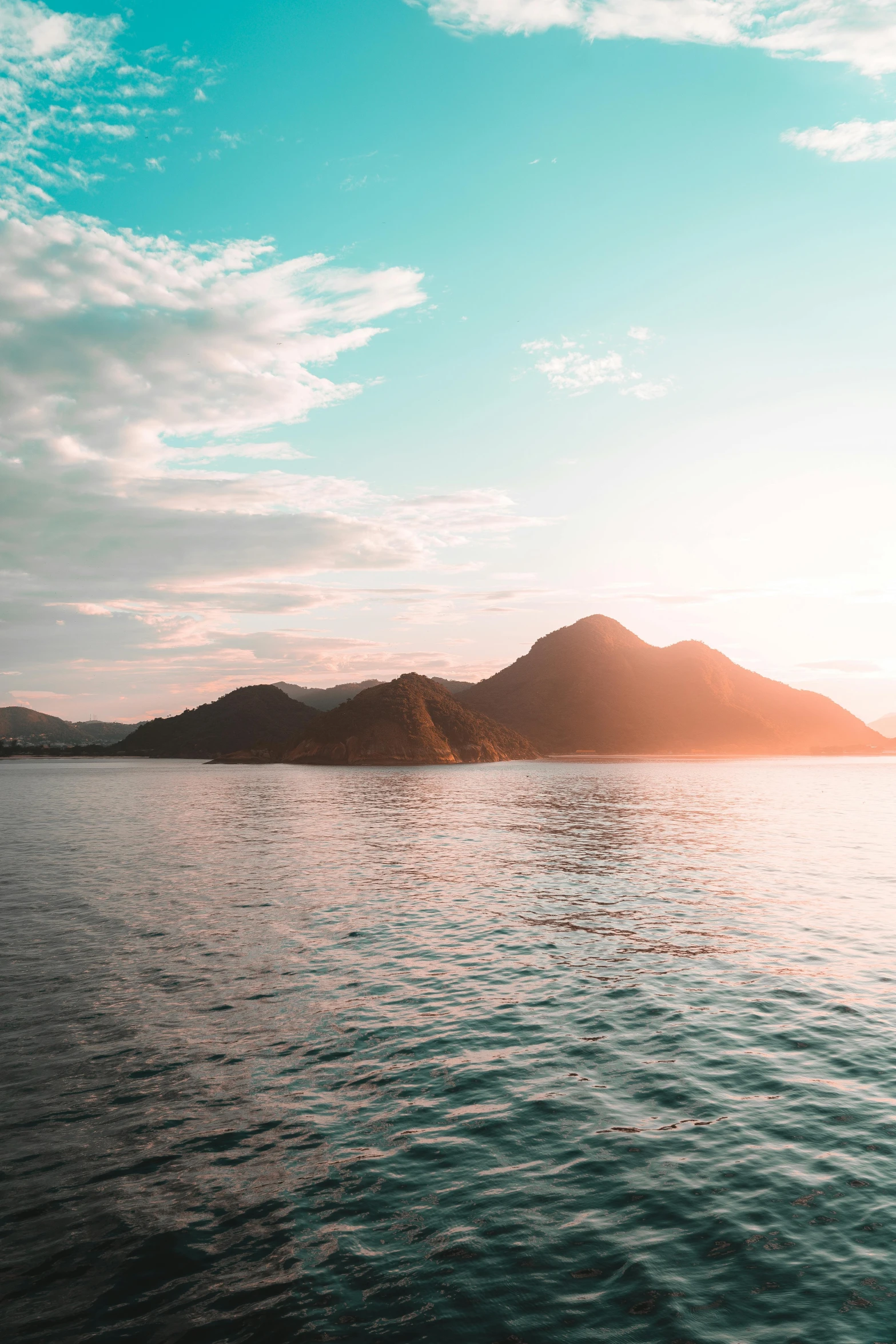 a body of water with mountains in the background, a picture, trending on unsplash, sumatraism, sunfaded, mediterranean island scenery, late afternoon light, multiple stories