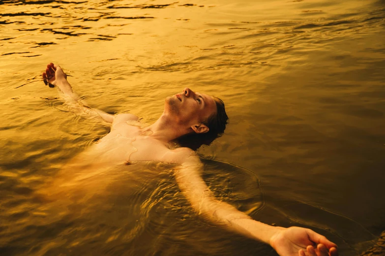 a person floating in a body of water, gold hour, he is very relaxed, hair floating covering chest, ignant