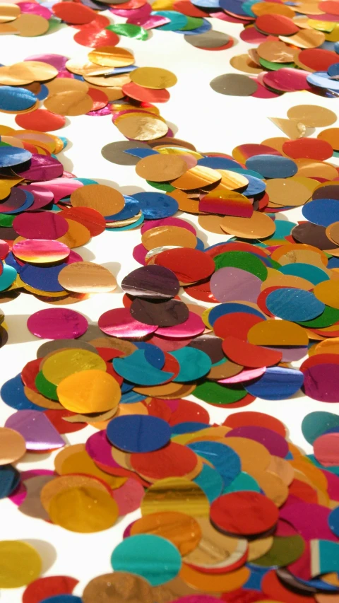 a white table topped with lots of colorful confetti, inspired by Howardena Pindell, pexels, metallic scales, 1960s-era, multicolor, circles