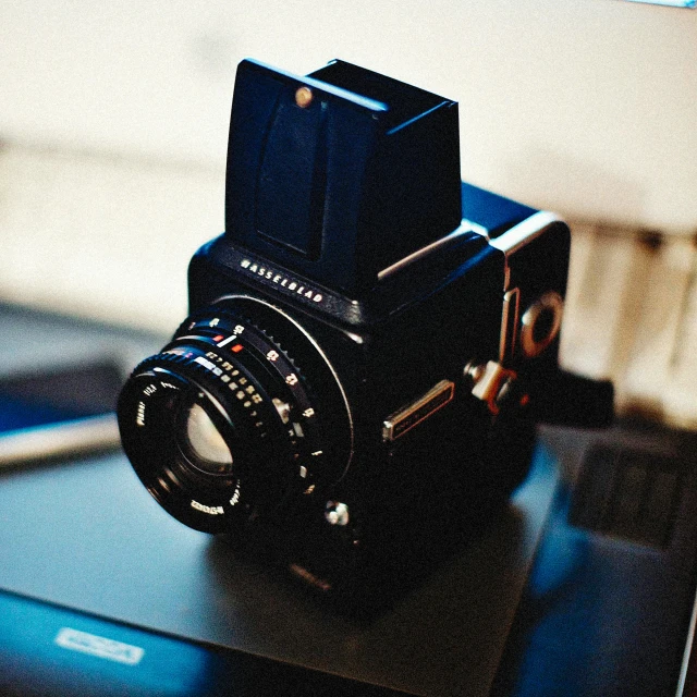 a camera sitting on top of a laptop computer, a polaroid photo, unsplash, photorealism, hasselblad medium format, hasselblade shot, old color photograph, looking intensely at the camera