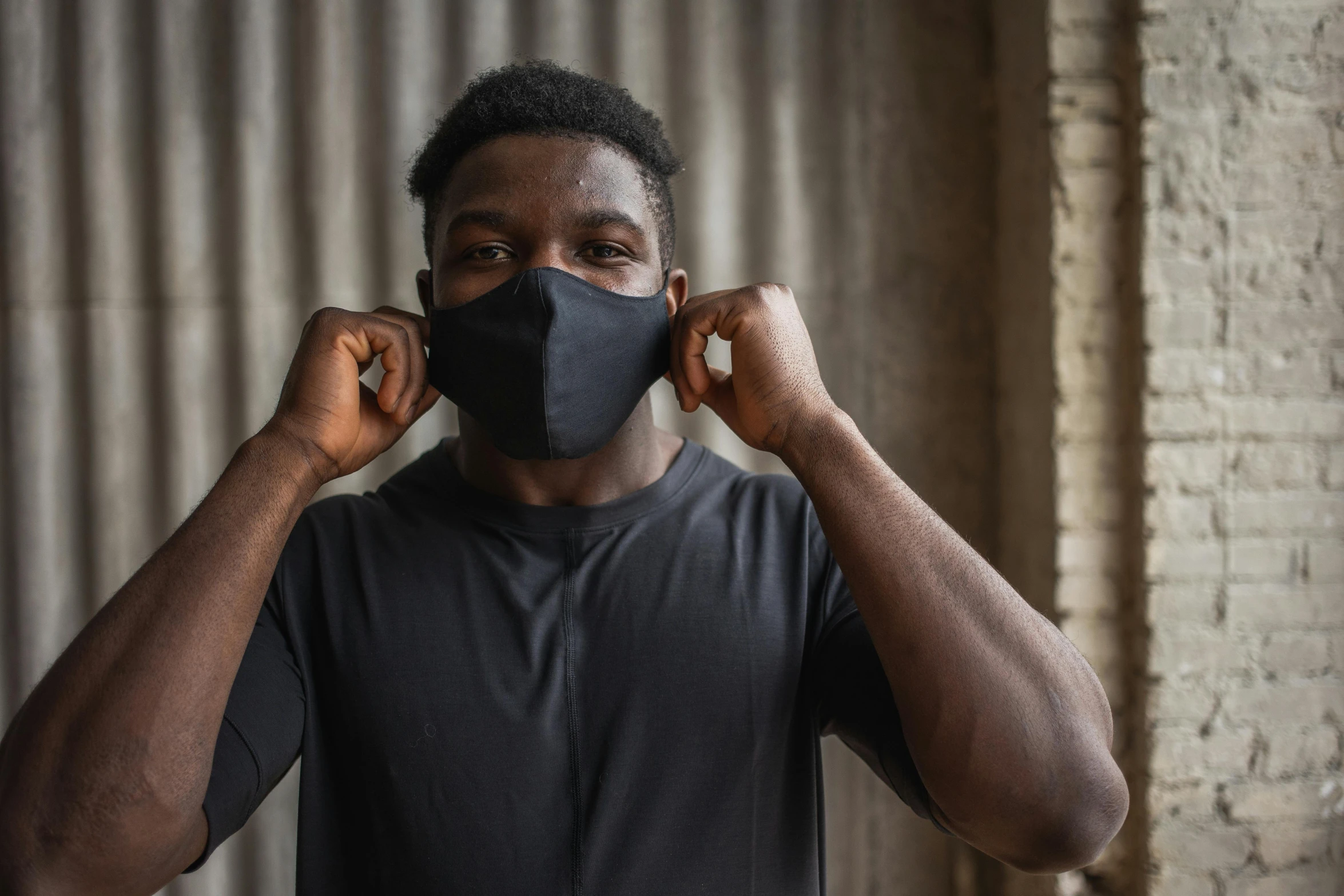 a man putting a mask on his face, he is wearing a black t-shirt, dark skinned, wearing fitness gear, thumbnail