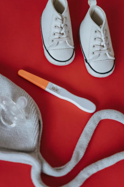 a pair of white shoes and a toothbrush on a red surface, trending on pexels, happening, gray and orange colours, toys, pregnancy, a folding knife