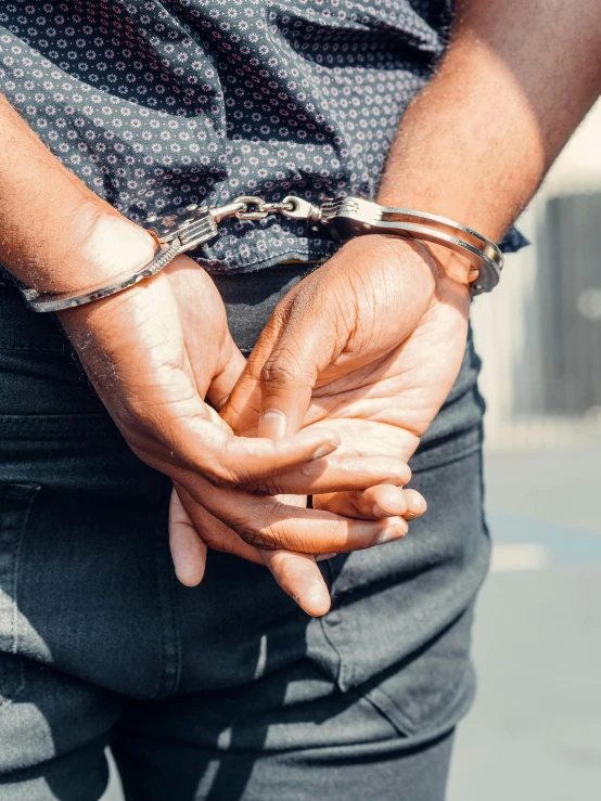 a close up of a person holding a pair of handcuffs, inspired by William Gouw Ferguson, trending on pexels, mugshot, lgbt, instagram story, black man