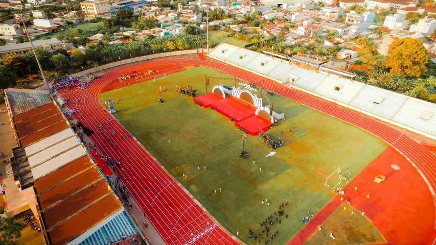 a group of people standing on top of a lush green field, a cartoon, pexels contest winner, quito school, sportspalast amphitheatre, yellow and red color scheme, drone speedways, covering the ground