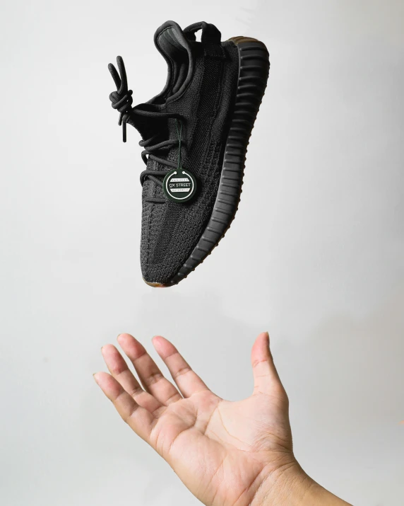 a person's hand reaching for a pair of black sneakers, inspired by Wang E, unsplash contest winner, hyperrealism, yeezus, miniature product photo, black in, full body photo