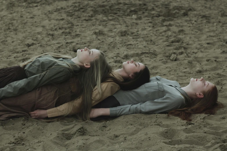 a couple of women laying on top of a sandy beach, by Attila Meszlenyi, unsplash, realism, film still from a horror movie, teenage girl, holding each other, ignant