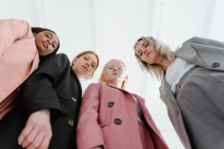 a group of women standing next to each other, trending on pexels, realism, wearing jacket, modest, looking up, girl in suit