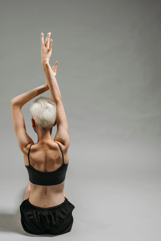 a woman sitting in the middle of a yoga pose, unsplash, minimalism, down left arm and back, raising an arm, bare back, full frame image