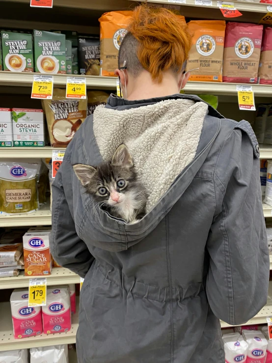 a woman standing in a store with a cat in her back, trending on reddit, grey hoodie opened, very accurate photo, about to consume you, high quality photo