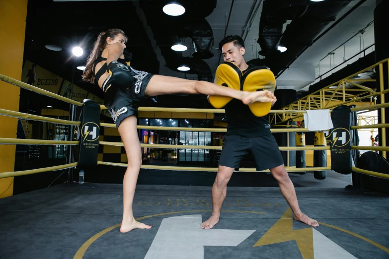 a man and a woman in a boxing ring, pexels contest winner, hurufiyya, yellow and black color scheme, heroic muay thai stance pose, square, female gigachad