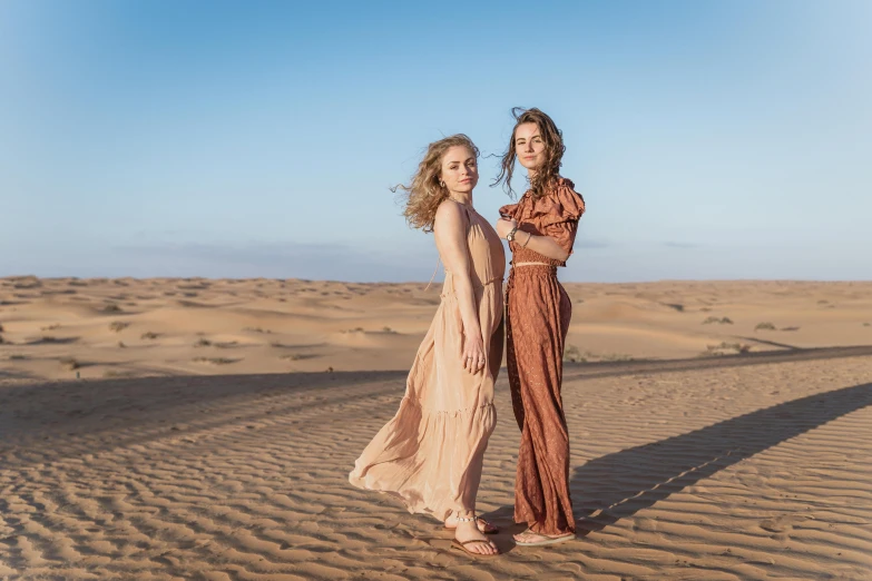 two women standing in the middle of a desert, by Liza Donnelly, trending on pexels, arabesque, photoshoot for skincare brand, in a beachfront environment, arabian nights inspired, girls resting