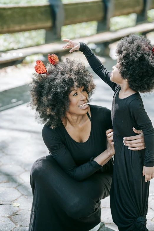 a woman sitting next to a little girl on a skateboard, black arts movement, big hair, crimson - black beehive, portrait featured on unsplash, playful pose of a dancer