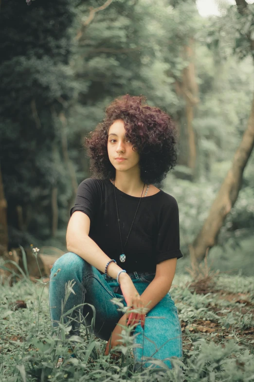 a woman sitting in the middle of a forest, short black curly hair, portrait featured on unsplash, wearing a dark shirt and jeans, avatar image