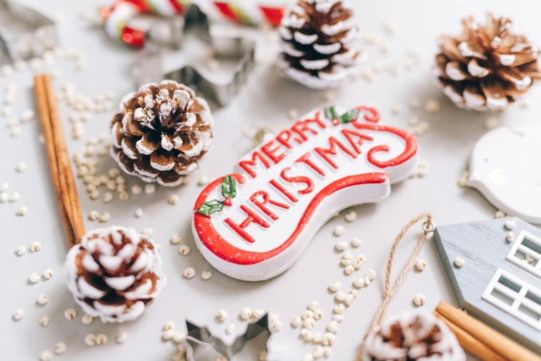 a white table topped with pine cones and ornaments, pexels, graffiti, background image, lettering, santa, very high resolution