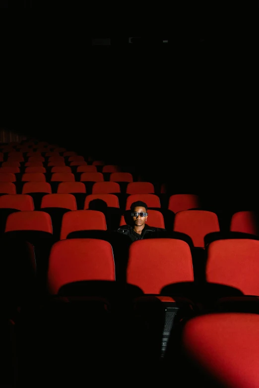 a man sitting in the middle of a row of red chairs, imdb, [ theatrical ], single, multiple stories
