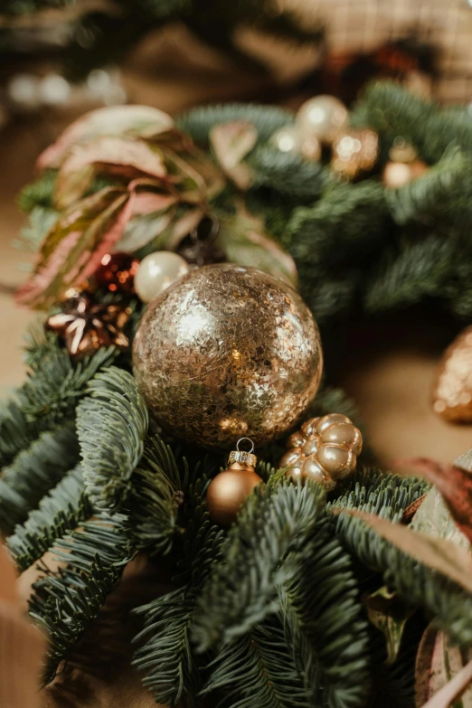 a close up of a christmas wreath on a table, by Jakob Emanuel Handmann, trending on unsplash, baroque, beige and gold tones, glass spheres, rustic setting, gold flake