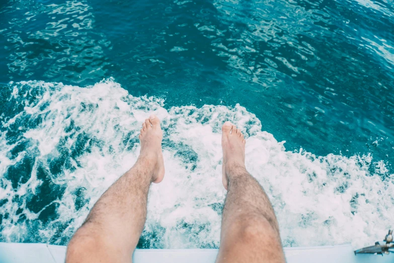 a man sitting on top of a boat in the ocean, by Adam Dario Keel, pexels contest winner, thighs thighs thighs thighs, floating. greenish blue, zachary corzine, juicy legs