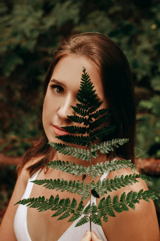 a woman holding a fern leaf in front of her face, a picture, inspired by Elsa Bleda, pexels contest winner, renaissance, attractive symmetrical face, girl with brown hair, headshot profile picture, waist high