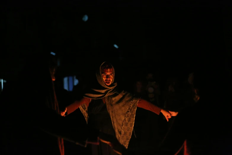 a man standing next to a fire in the dark, hurufiyya, face is wrapped in a black scarf, people enjoying the show, ignant, actress