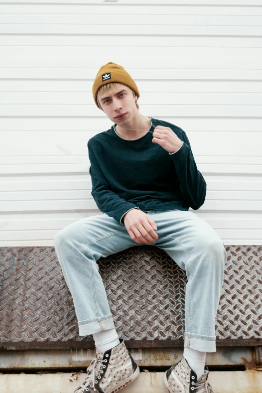 a young man is sitting on a bench, trending on pexels, baggy clothing and hat, corduroy, skinny caucasian young man, promotional image