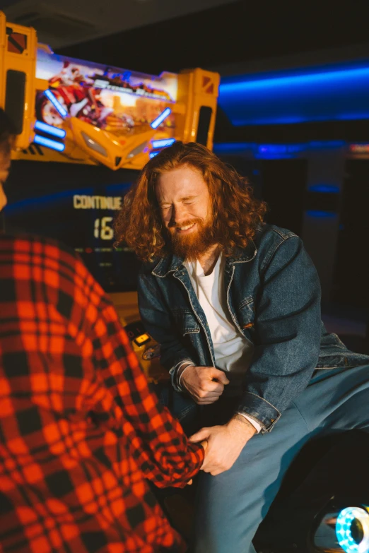 a man and a woman playing a video game, medium long wavy ginger hair, at a bar, cinestill 800t 50mm eastmancolor, smiling at each other