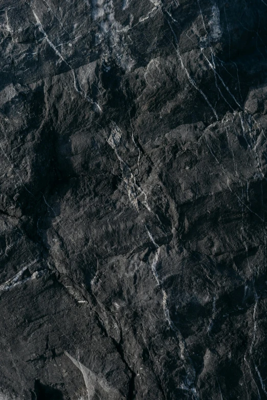 a man riding a snowboard on top of a snow covered slope, an album cover, by Jacob Toorenvliet, trending on unsplash, high resolution coal texture, extremely detailed rocky crag, black lung detail, panel of black