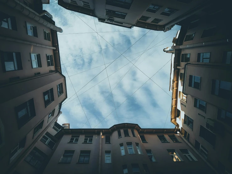 a very tall building with a blue sky in the background, inspired by Alexander Rodchenko, unsplash contest winner, a wide open courtyard in an epic, tangled overhead wires, fisheye lens photo, alessio albi