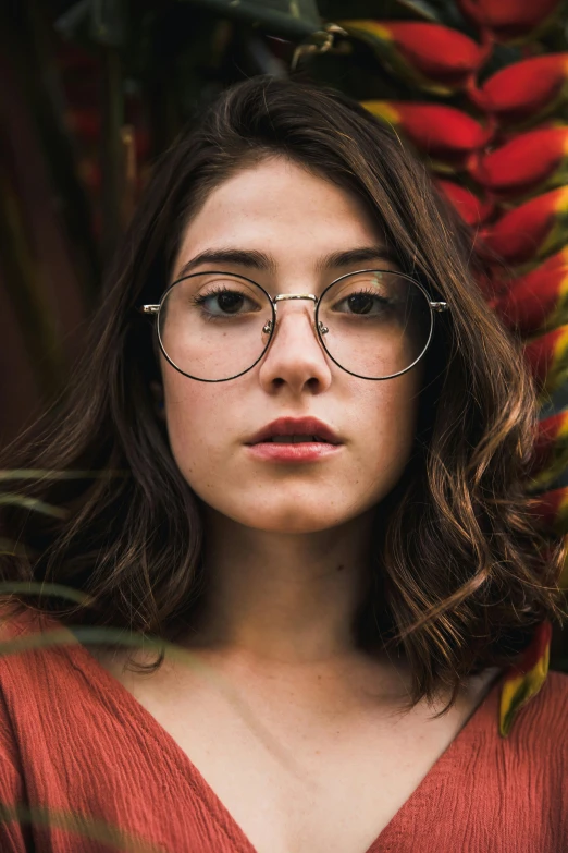 a woman wearing glasses standing in front of a bunch of flowers, trending on pexels, renaissance, alena aenami and lilia alvarado, cinematic headshot portrait, round glasses potter, promotional image