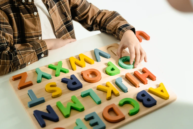 a child playing with a wooden alphabet puzzle, by Juan O'Gorman, trending on pexels, letterism, on a wooden tray, multi colour, teacher, carving