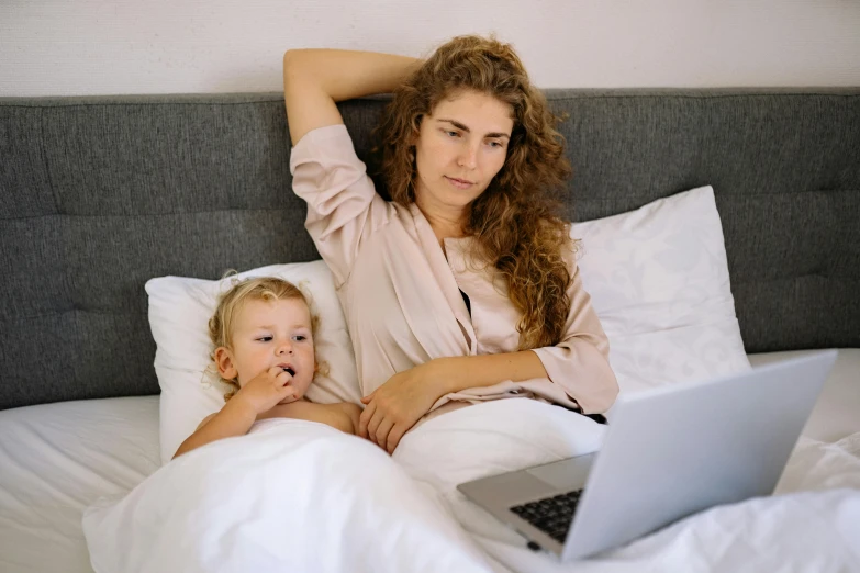 a woman and child laying in bed with a laptop, by Carey Morris, pexels, happening, avatar image, casually dressed, movies, white