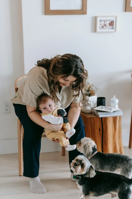 a woman holding a baby and a dog, by Nina Hamnett, trending on pexels, modernism, indoor picture, gif, stuffed animal, sitting down