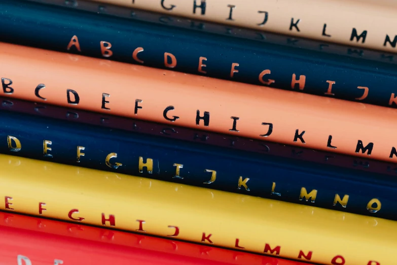 a stack of pencils sitting on top of each other, an album cover, unsplash, letterism, alphabet soup, children's, navy, latex