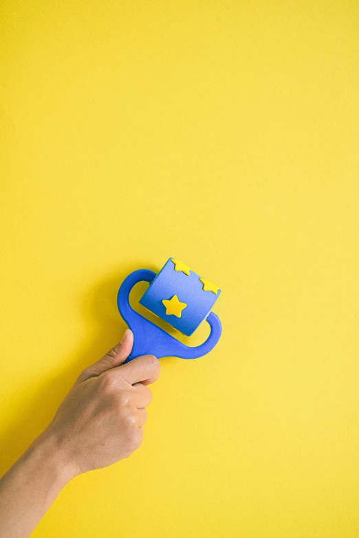 a person holding a pair of scissors on a yellow background, a jigsaw puzzle, by Sven Erixson, pexels contest winner, blue wizard hat, stars on top of the crown, happy meal toy, blue and yellow color scheme