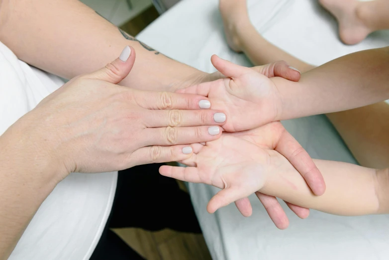 a group of people putting their hands together, by Emma Andijewska, acupuncture treatment, light toned, fan favorite, women hand