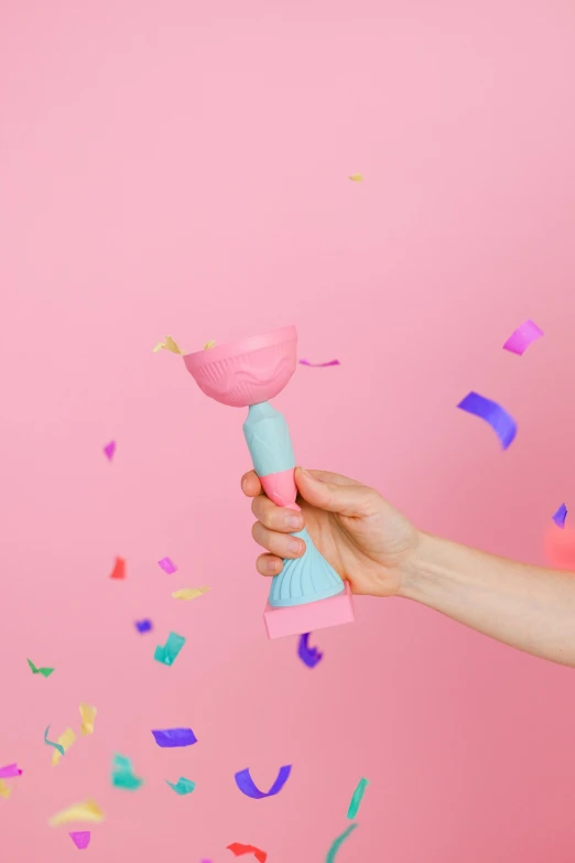 a person holding a pink object with confetti sprinkles, speculum, teal and pink, holding a torch, full product shot