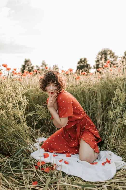 a woman sitting in a field of tall grass, pexels contest winner, color field, red floral dress, polka dot, orange tones, instagram post