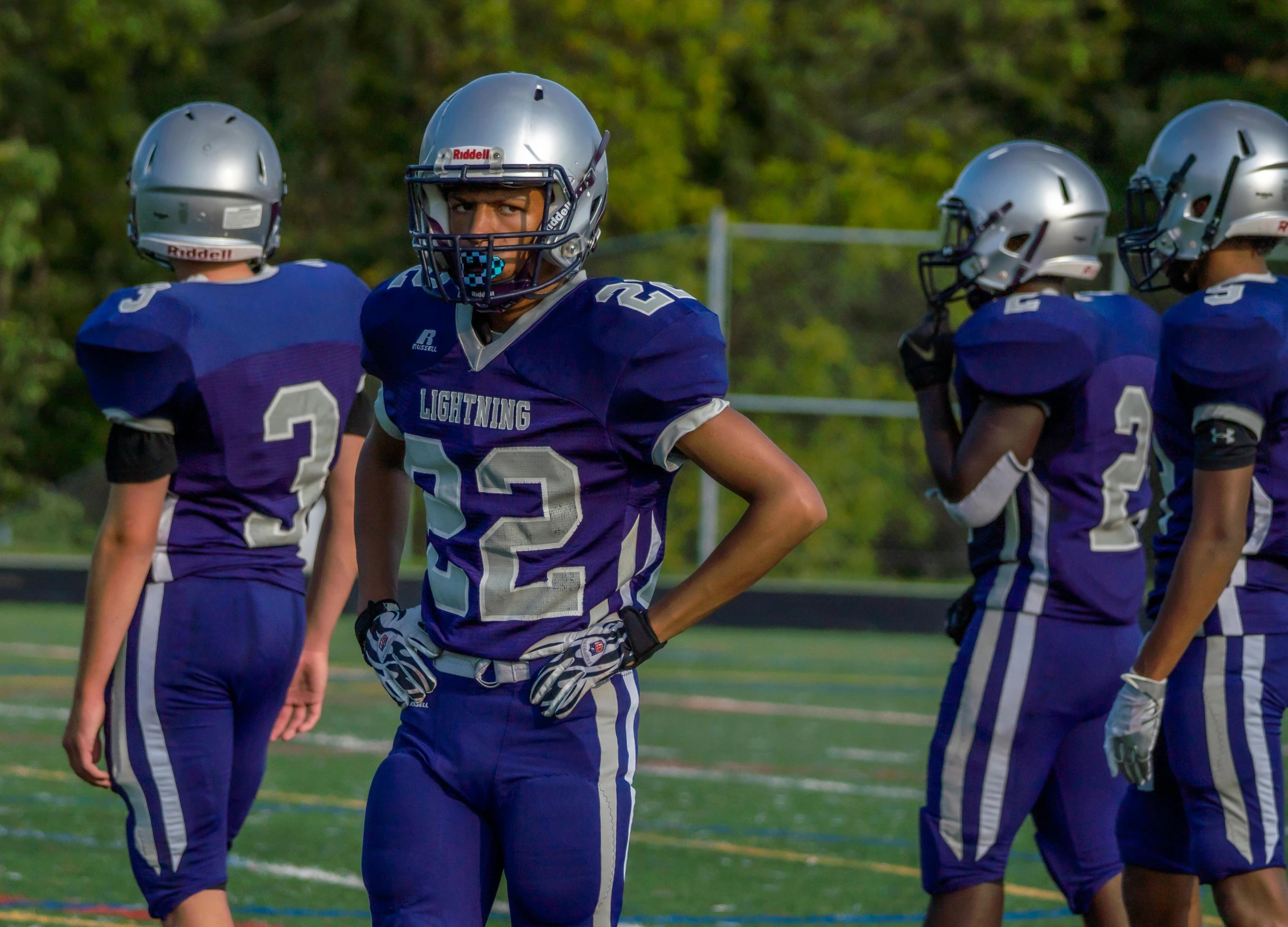 a group of young men standing on top of a field, by Sam Dillemans, unsplash, happening, football armor, thin straight purple lines, looking to his side, anthony moravian