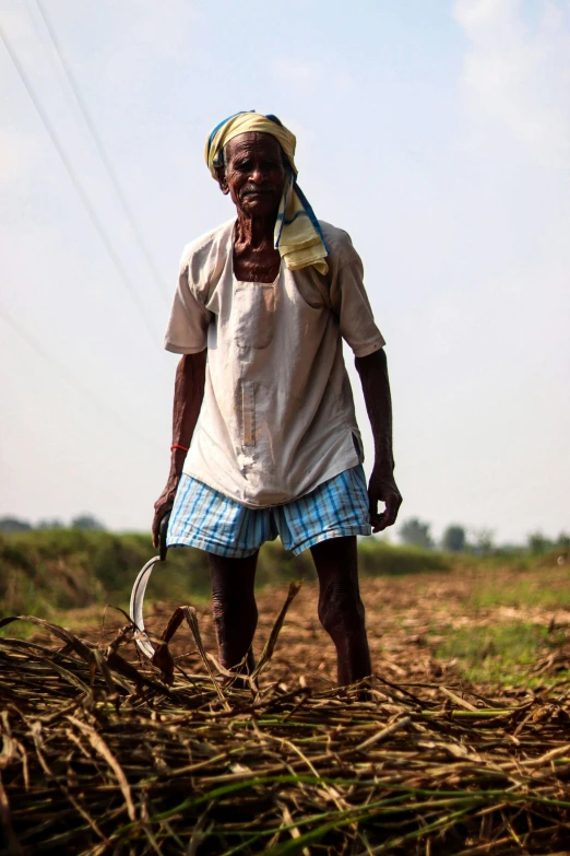 a man standing in the middle of a field, by Rajesh Soni, using a spade, emaciated, no cropping, unedited