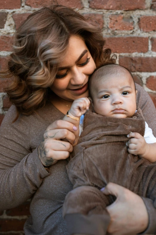 a woman holding a baby wrapped in a blanket, by Jason Felix, unsplash, brown clothes, plus-sized, hispanic, chocolate