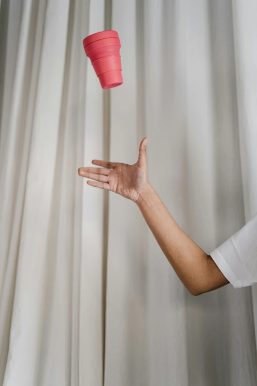 a man throwing a red cup into the air, pexels contest winner, kinetic art, white and pink cloth, hanging veins, hanging out with orbs, ( ( theatrical ) )