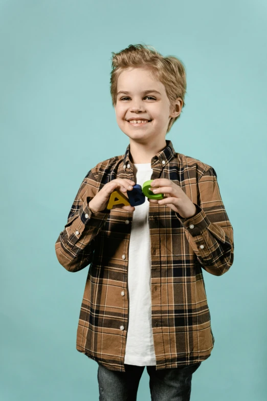 a young boy standing in front of a blue background, a rubik's cube, holding an avocado in his hand, wearing a flannel shirt, detailed product image