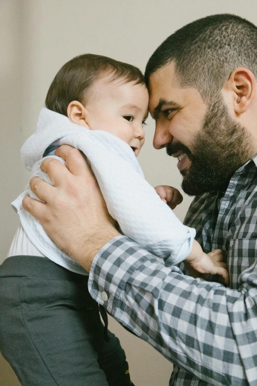 a man holding a baby in his arms, pexels, jen atkin, sam nassour, press shot, small beard