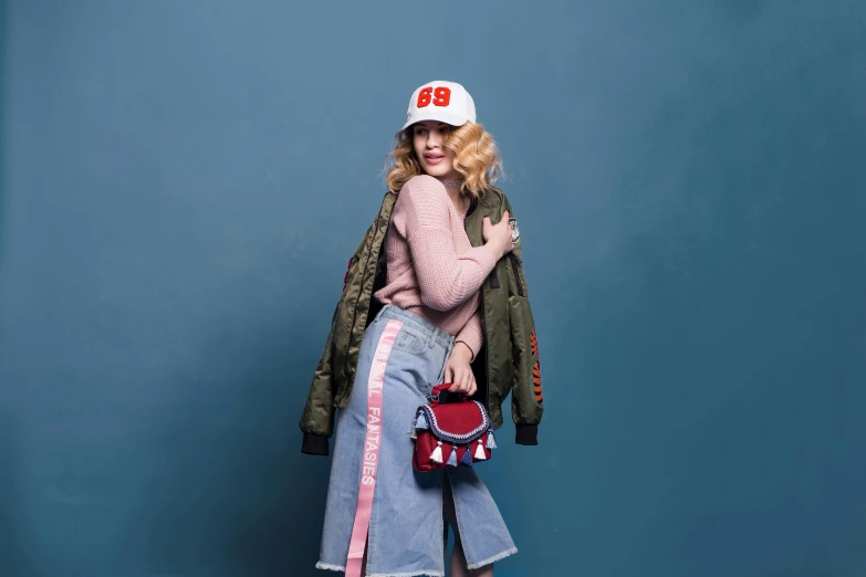 a woman standing in front of a blue wall, inspired by Elsa Bleda, pop art, wearing baseball cap, 9 9 designs, julia garner, various posed