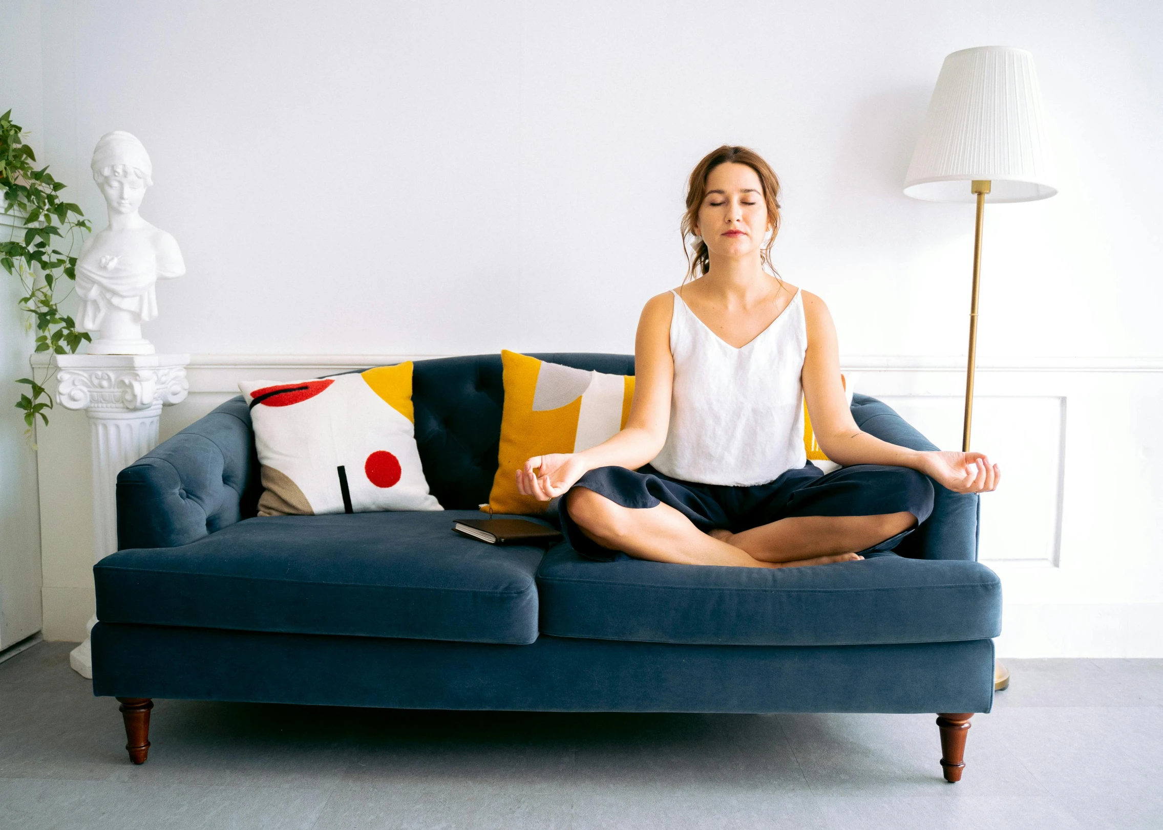 a woman sitting on top of a blue couch, by Rachel Reckitt, minimalism, yoga meditation pose, on a couch, chakras, 30-year-old french woman